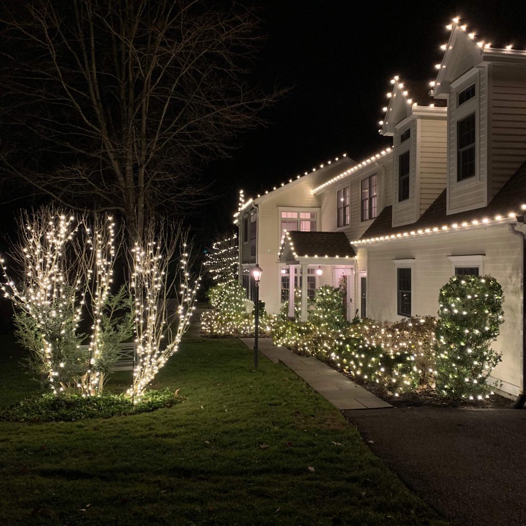 Christmas lights decorating a Greenwich CT home, trees, and landscape.