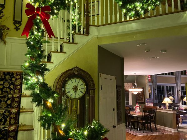 Christmas garland installation along an indoor staircase with warm white lights and red bows.