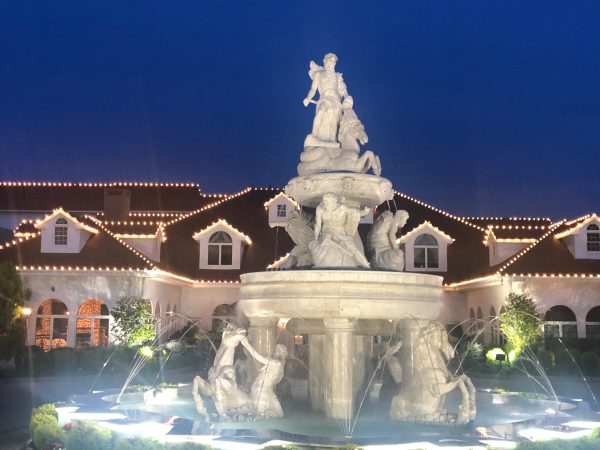 Commercial Christmas light installation featuring illuminated rooflines and a decorative fountain at a property in New Rochelle, NY.